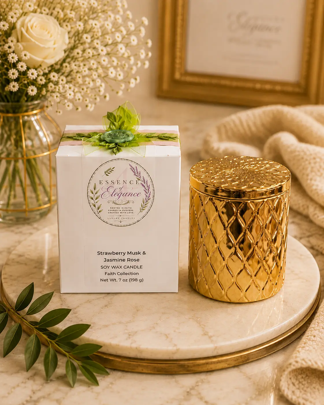 Essence of Elegance gold candle beside its Strawberry Musk & Jasmine Rose box